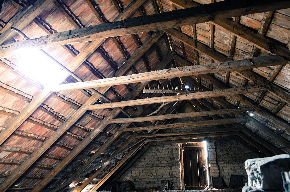 Daylight falling through an opening onto the rafters and boards of an old unfinished attic