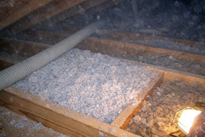 An insulation hose filling a joist bay with fresh loose fill