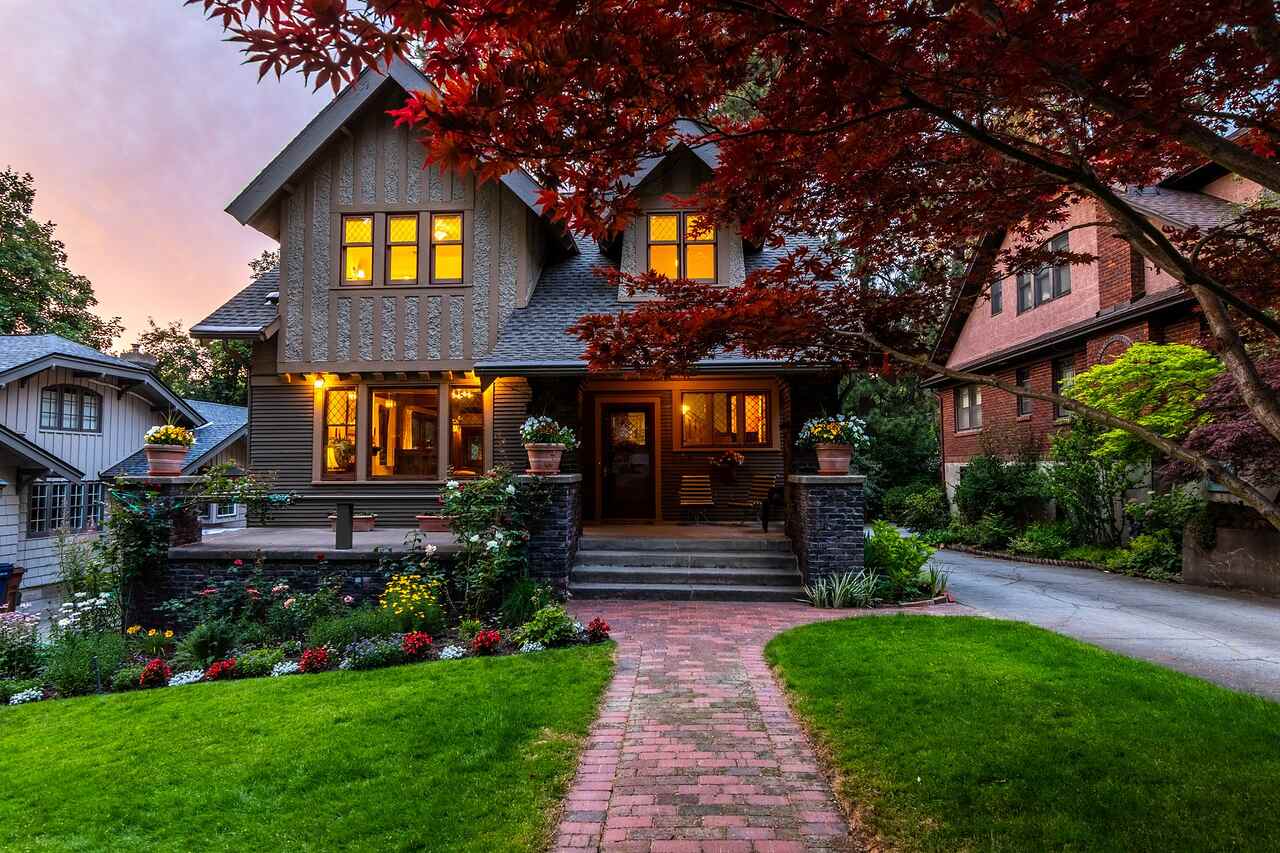 A suburban house with a deep front porch and mature planting photographed at twilight