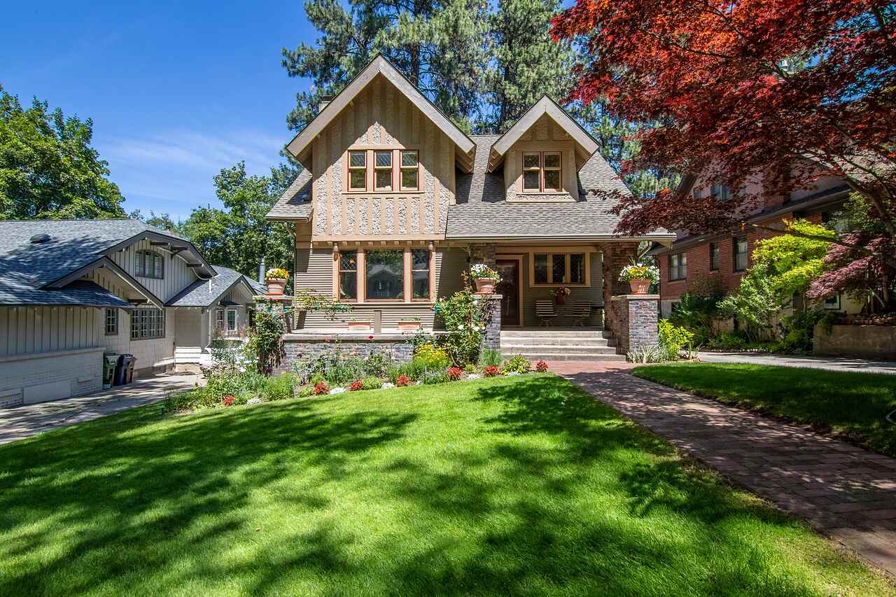 A well-kept older house with a manicured lawn and trimmed planting