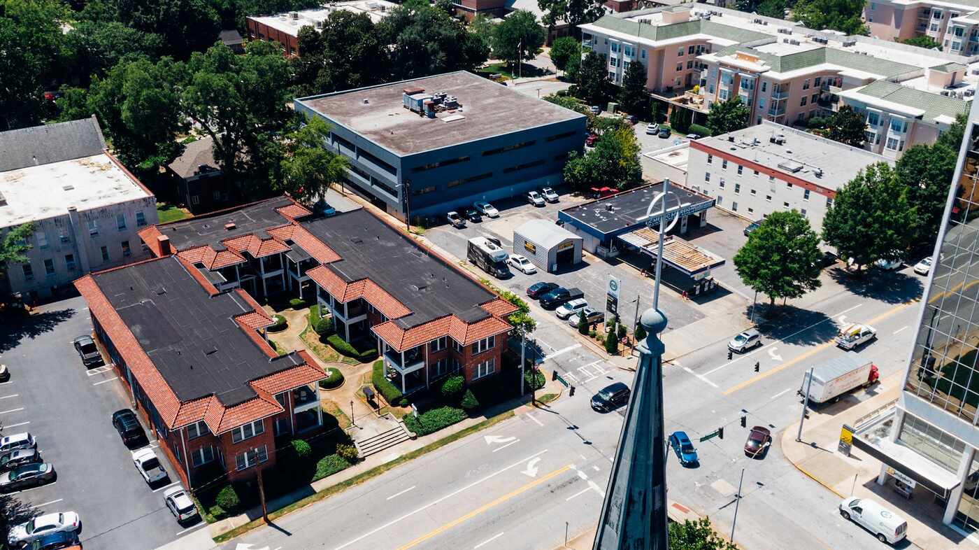 An aerial view of low commercial buildings, streets and parking along a town center