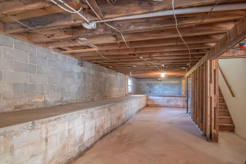 An unfinished under-floor space with exposed beams and block walls