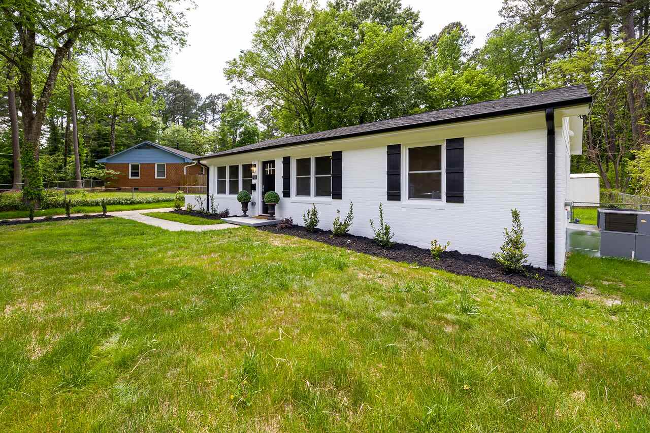 A low single-story house with a wide lawn and clipped planting