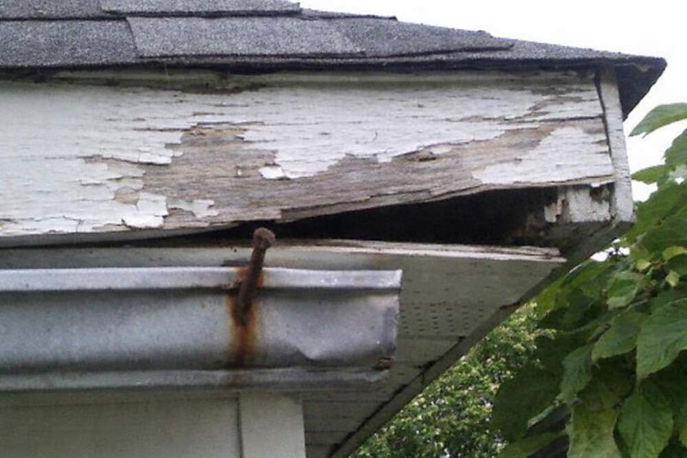 A gap opening between a fascia board and the soffit beneath a shingled eave