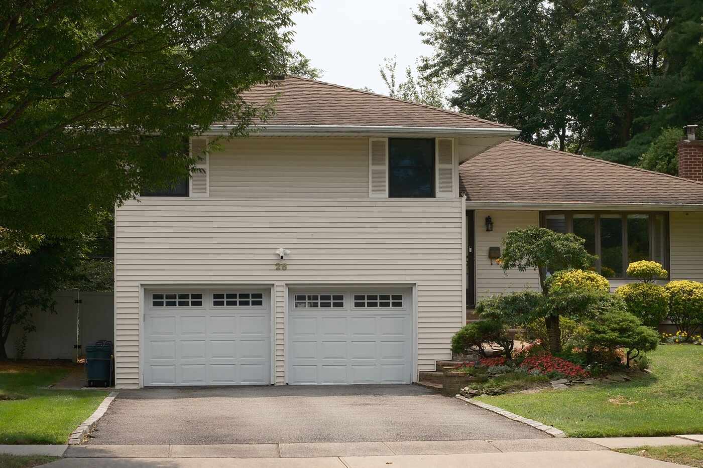 A house with a double garage and planted beds stepping up from the driveway