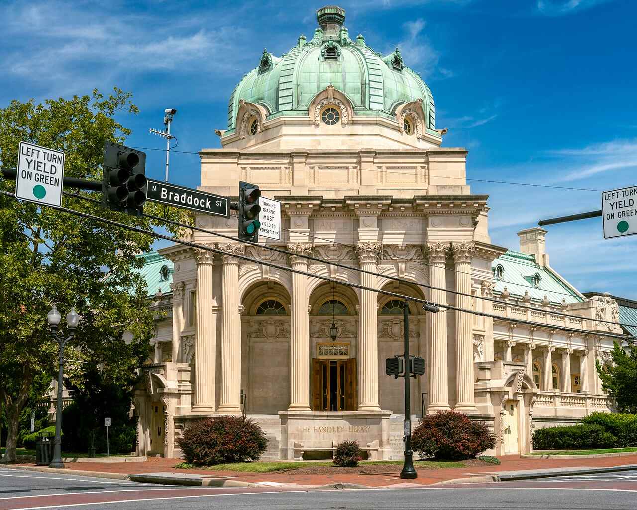 A civic building with a copper dome and heavy stone arches under a clear sky