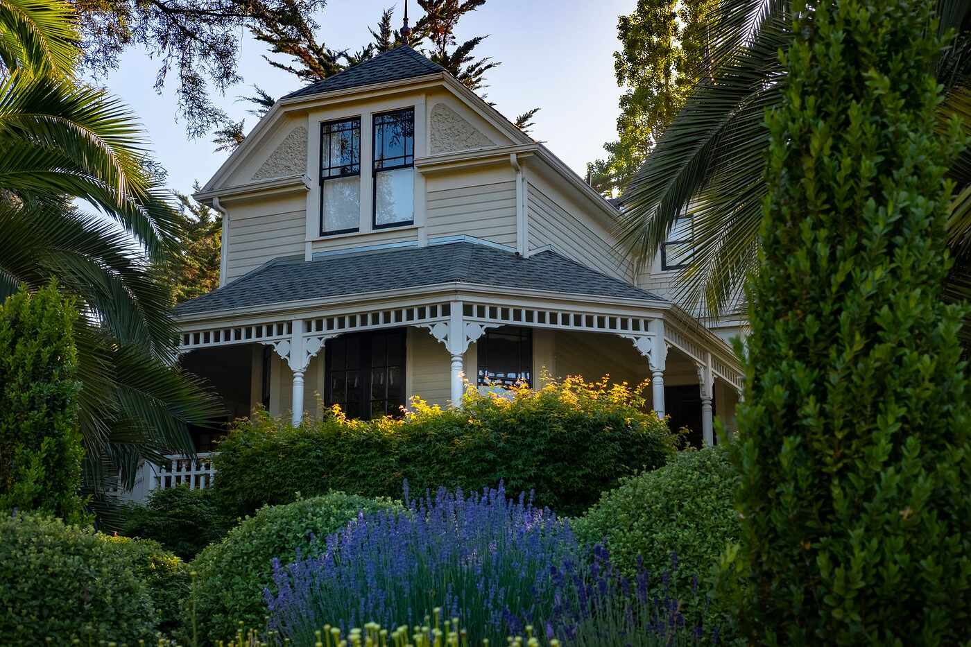 A Victorian house with a deep porch standing above a planted front garden
