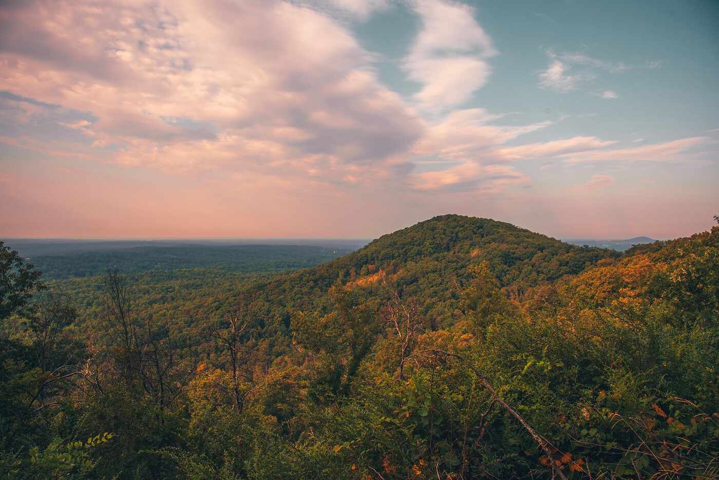 A green wooded ridge rising under a pale evening sky